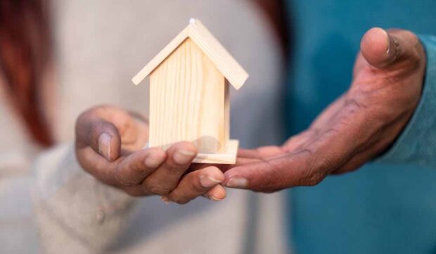 Homeowner reviewing mortgage refix options while holding a small house model