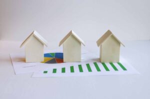 House models on financial charts representing mortgage refinancing and comparing loan options between banks