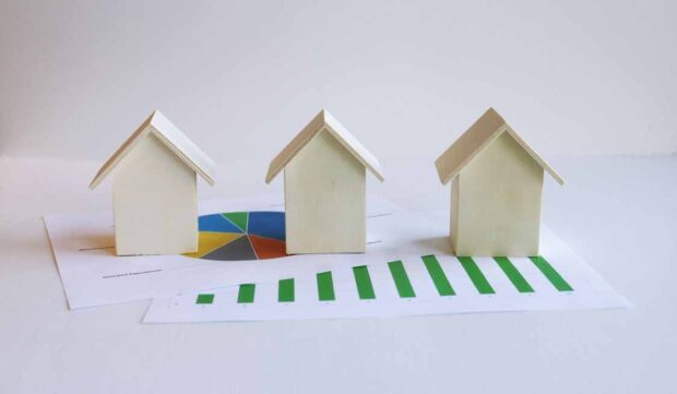 House models on financial charts representing mortgage refinancing and comparing loan options between banks