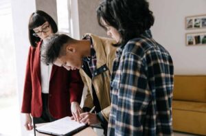 First-home buyer signing mortgage documents while discussing how a student loan may affect borrowing capacity